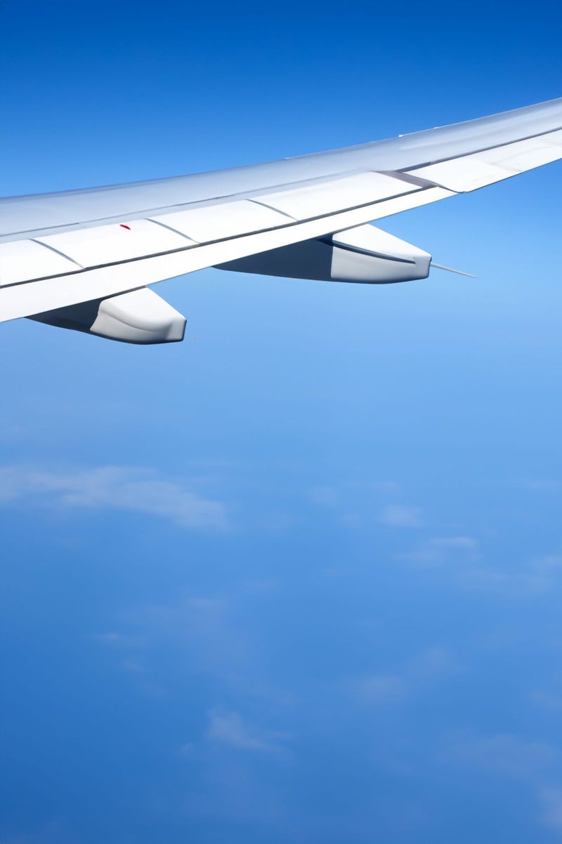 Aircraft wing seen through a cabin window above the clouds at sunset