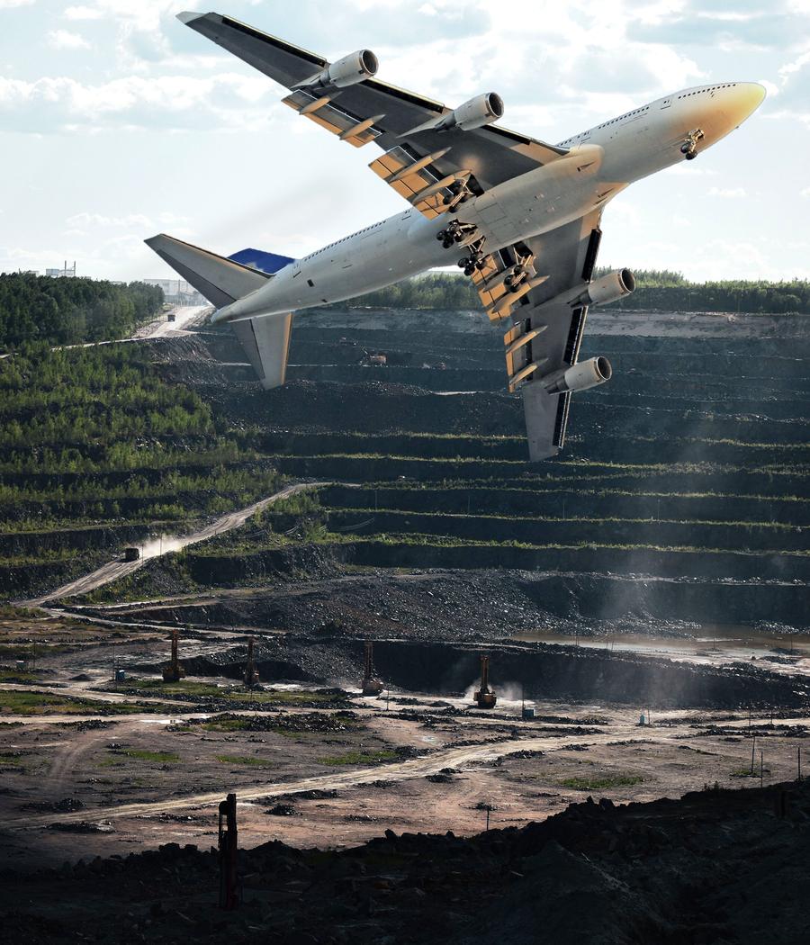 A large Boeing 747 banking steeply over the terraced benches of a vast open-pit mine