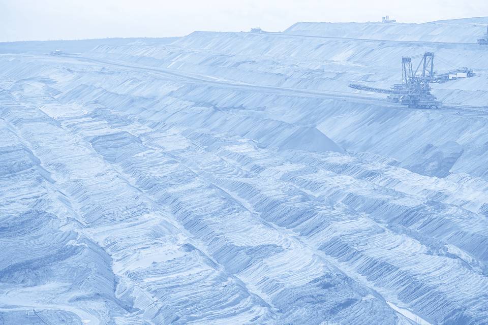 Terraced layers of an open-pit mine in soft blue tones