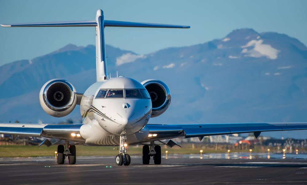 A business jet taxiing with mountains behind